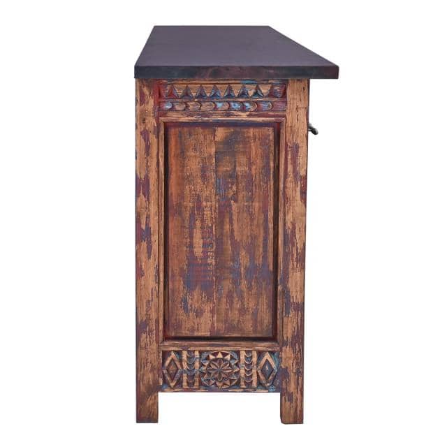A rustic, hand-carved wooden cabinet with a distressed finish showing brown and blue tones, topped with a dark slate or stone countertop, isolated on a white background.
