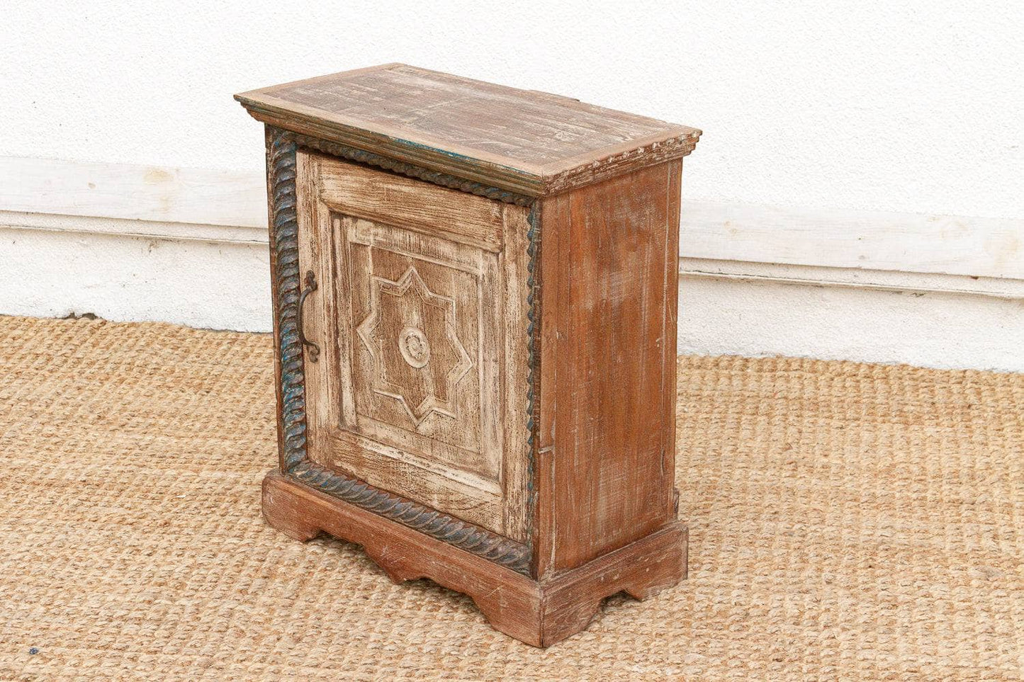 Wooden side table with decorative carvings on a textured surface