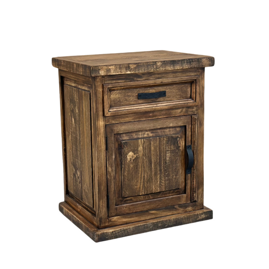 Angled view: Oasis rustic pine nightstand with one drawer, a paneled cabinet door and dark metal hardware in Far West finish