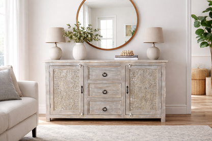Living room with a wooden sideboard, round mirror, and decorative items.