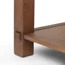 Close-up of a wooden furniture corner showing a medium brown wood grain surface and a small metal bracket connection.