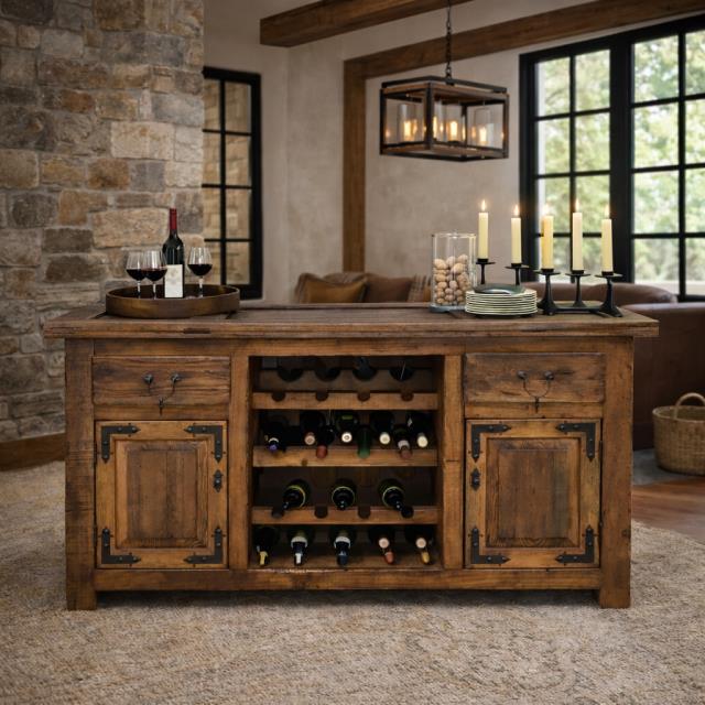 A rustic wooden wine cooler and bar cart with a built-in wine rack, shown in a styled home interior with stone walls, candles, and wine glasses.