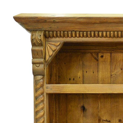 Close-up of a rustic wooden cabinet corner with carved decorative brackets, a rope-textured pillar, and a horizontal shelf, shown against a plain white background.