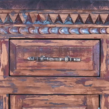 Close-up of a rustic wooden cabinet or dresser drawer with a distressed brown finish, carved triangular detailing along the top, and a metal pull handle.