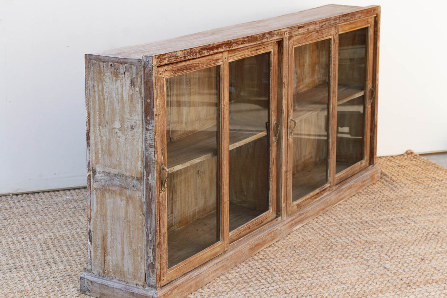 Wooden cabinet with glass doors on a textured floor