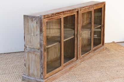 Wooden cabinet with glass doors on a textured floor