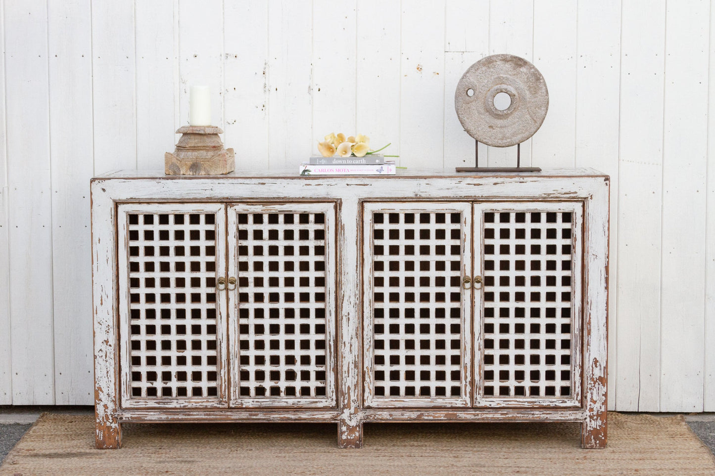 Vintage-style sideboard with lattice doors against a white wooden wall.