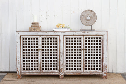 Vintage-style sideboard with lattice doors against a white wooden wall.