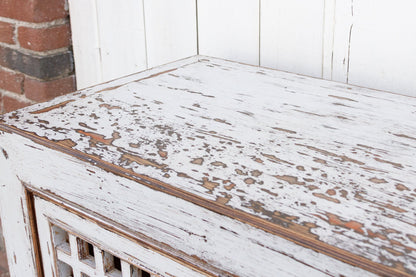 Weathered wooden bench with peeling paint in a rustic setting.