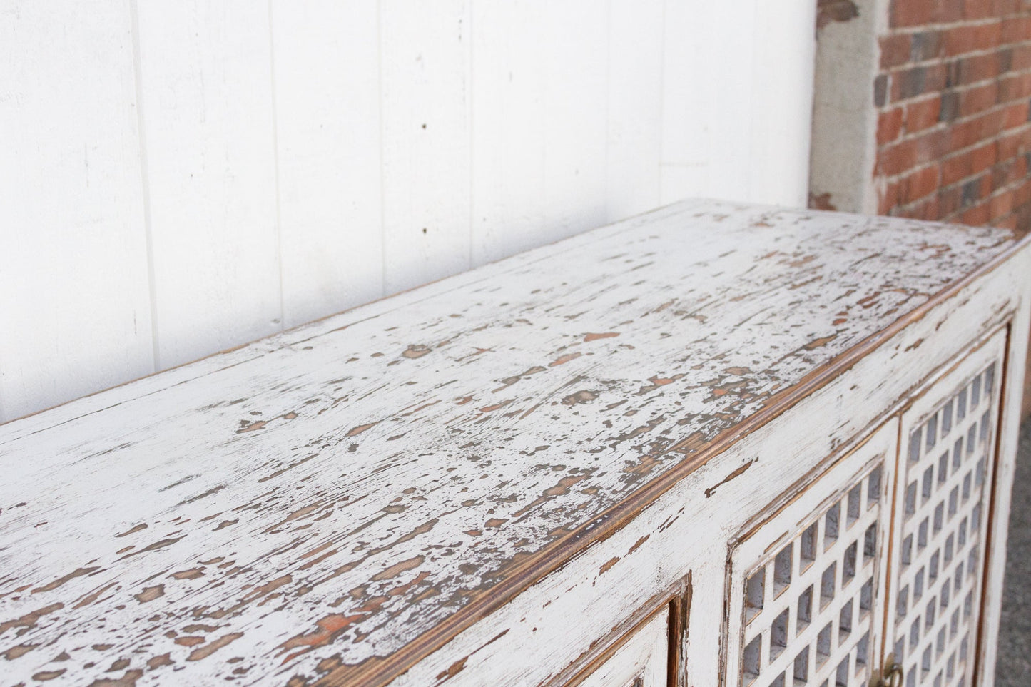 Weathered wooden surface with a white wall and brick wall in the background