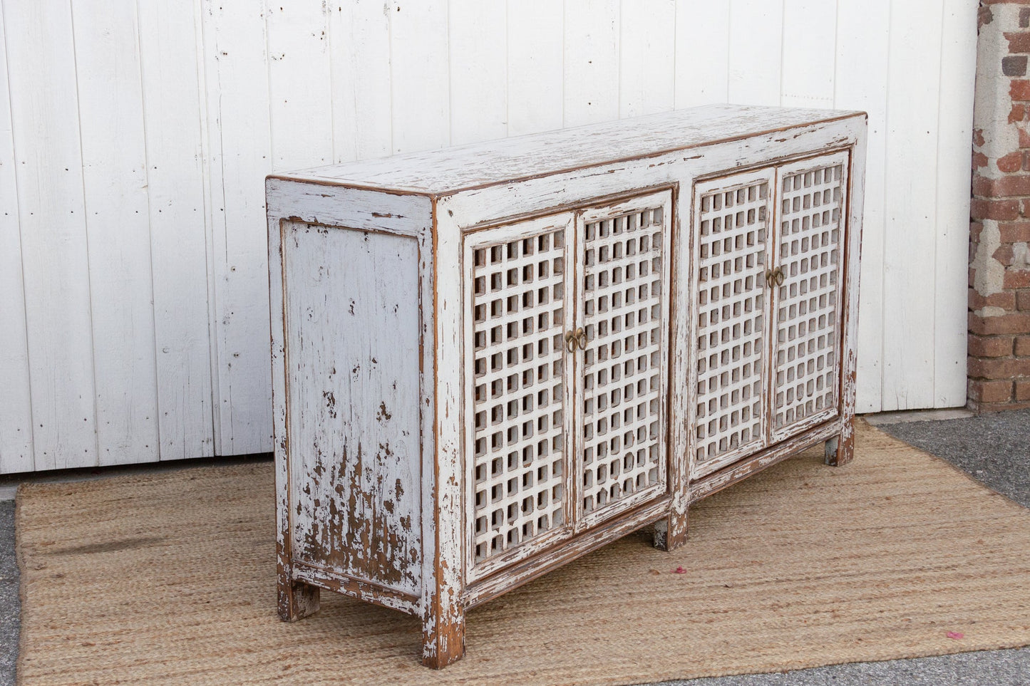 Vintage-style wooden sideboard with lattice doors against a white wall.