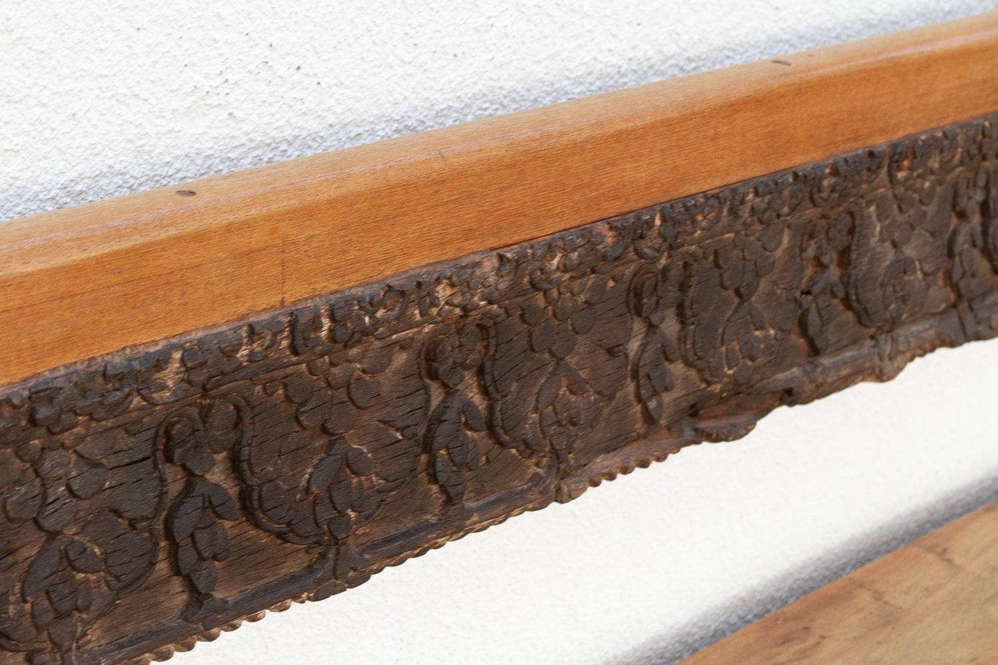 Close-up of a wooden frame with intricate carvings on a white background
