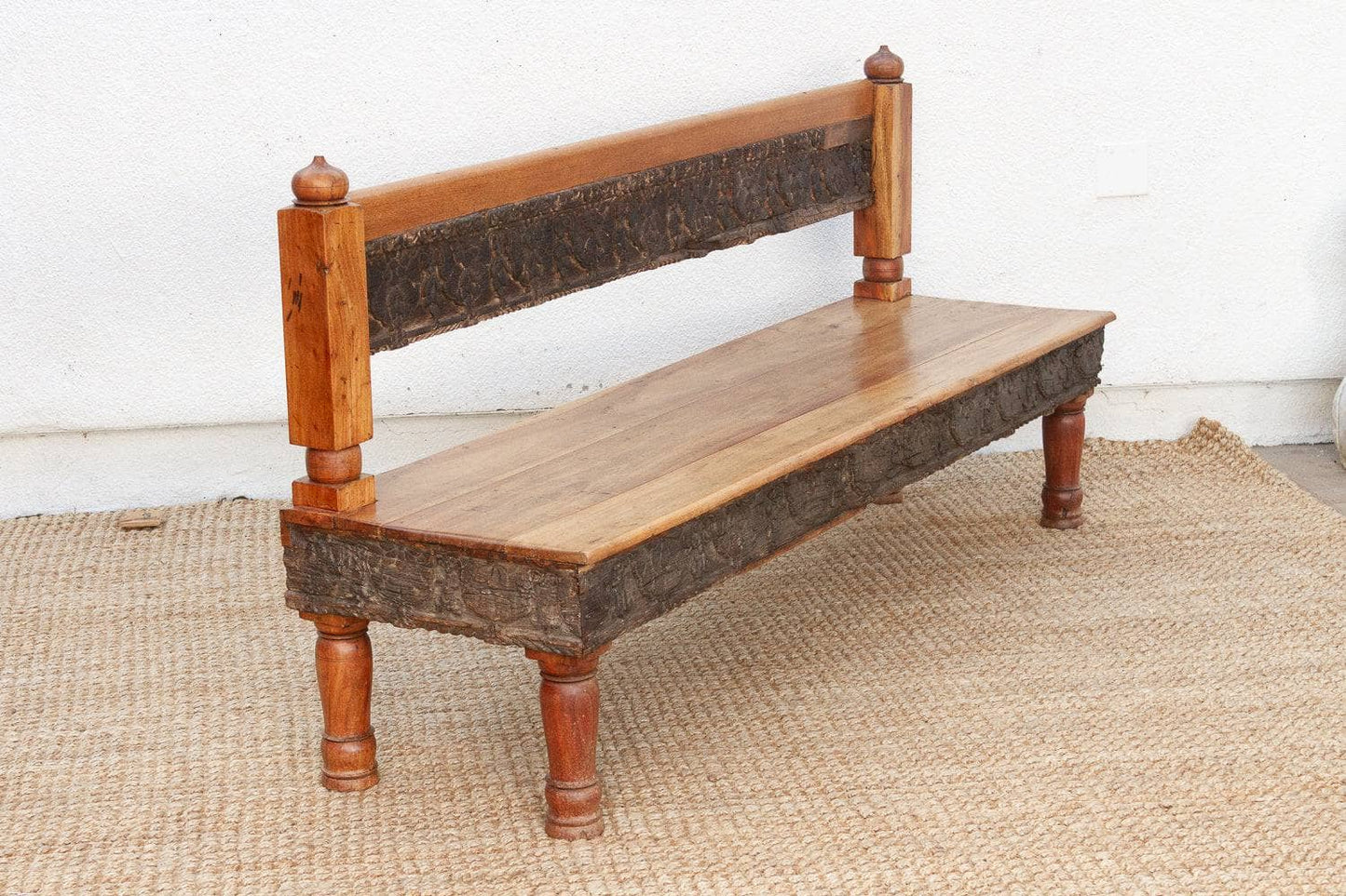 Wooden bench with a textured backrest on a jute rug