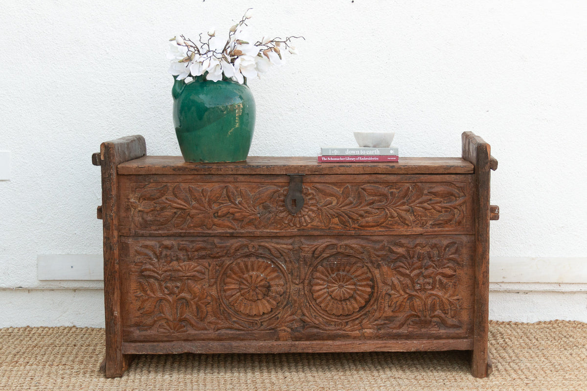 Wooden chest with floral carvings on a white wall background