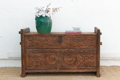 Wooden chest with floral carvings on a white wall background