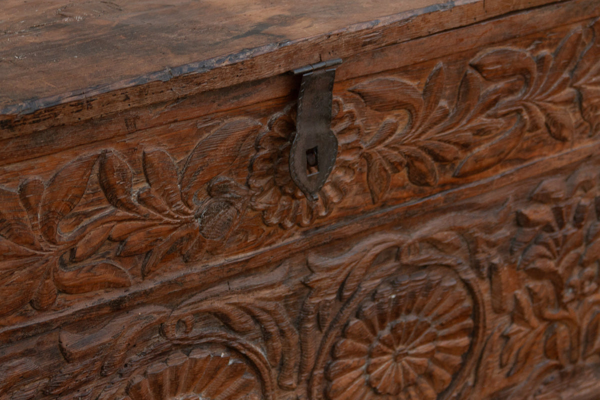 Wooden box with intricate carvings and a metal latch.