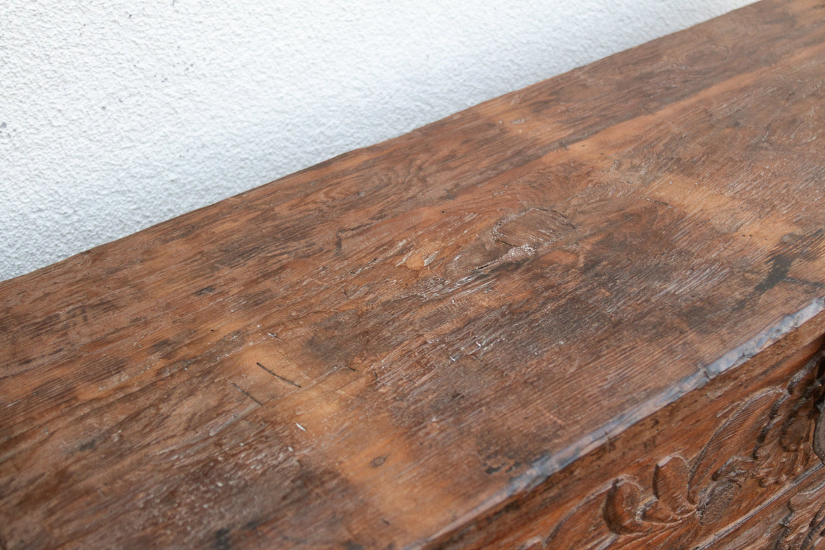 Close-up of a wooden surface with intricate carvings on a light gray background