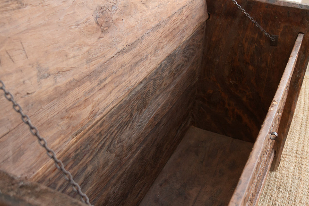 Close-up of a wooden box with a chain, showing signs of wear.