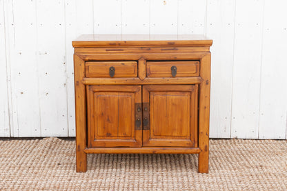 Wooden cabinet with two doors and two drawers against a white wooden panel background