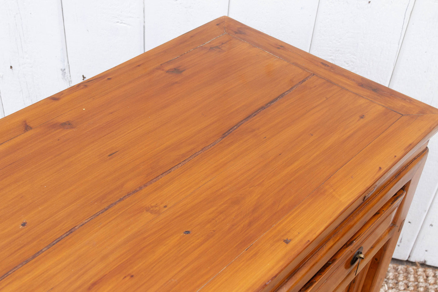 Wooden dresser with a white paneled wall background