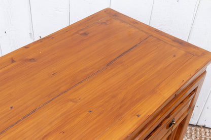 Wooden dresser with a white paneled wall background