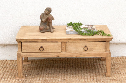 Wooden coffee table with decorative items on a textured surface
