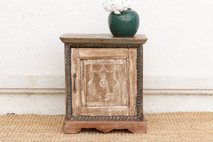 Wooden side table with decorative design on a white wall background