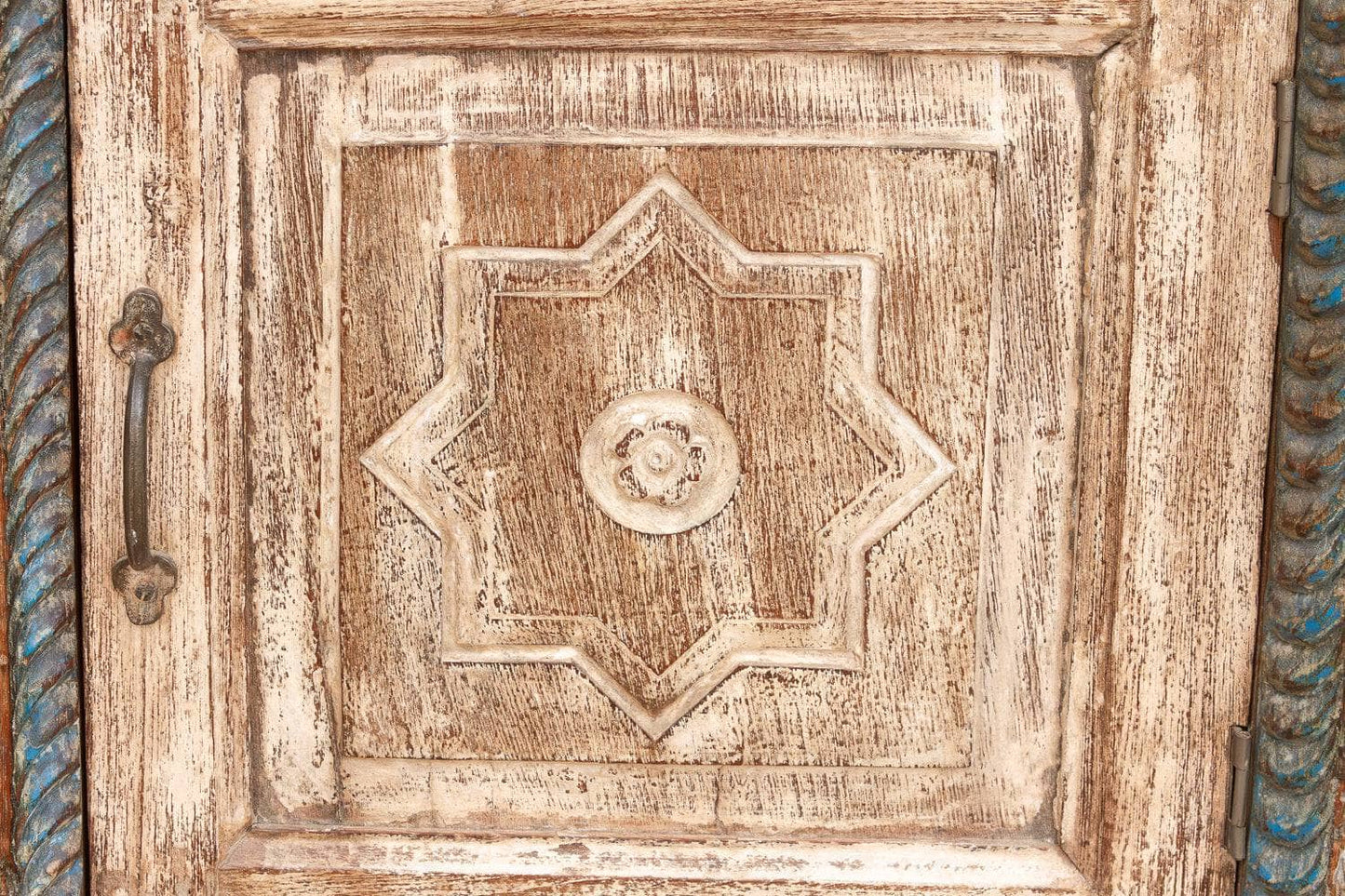 Close-up of a wooden door with decorative carvings and a metal handle.