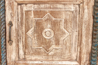 Close-up of a wooden door with decorative carvings and a metal handle.