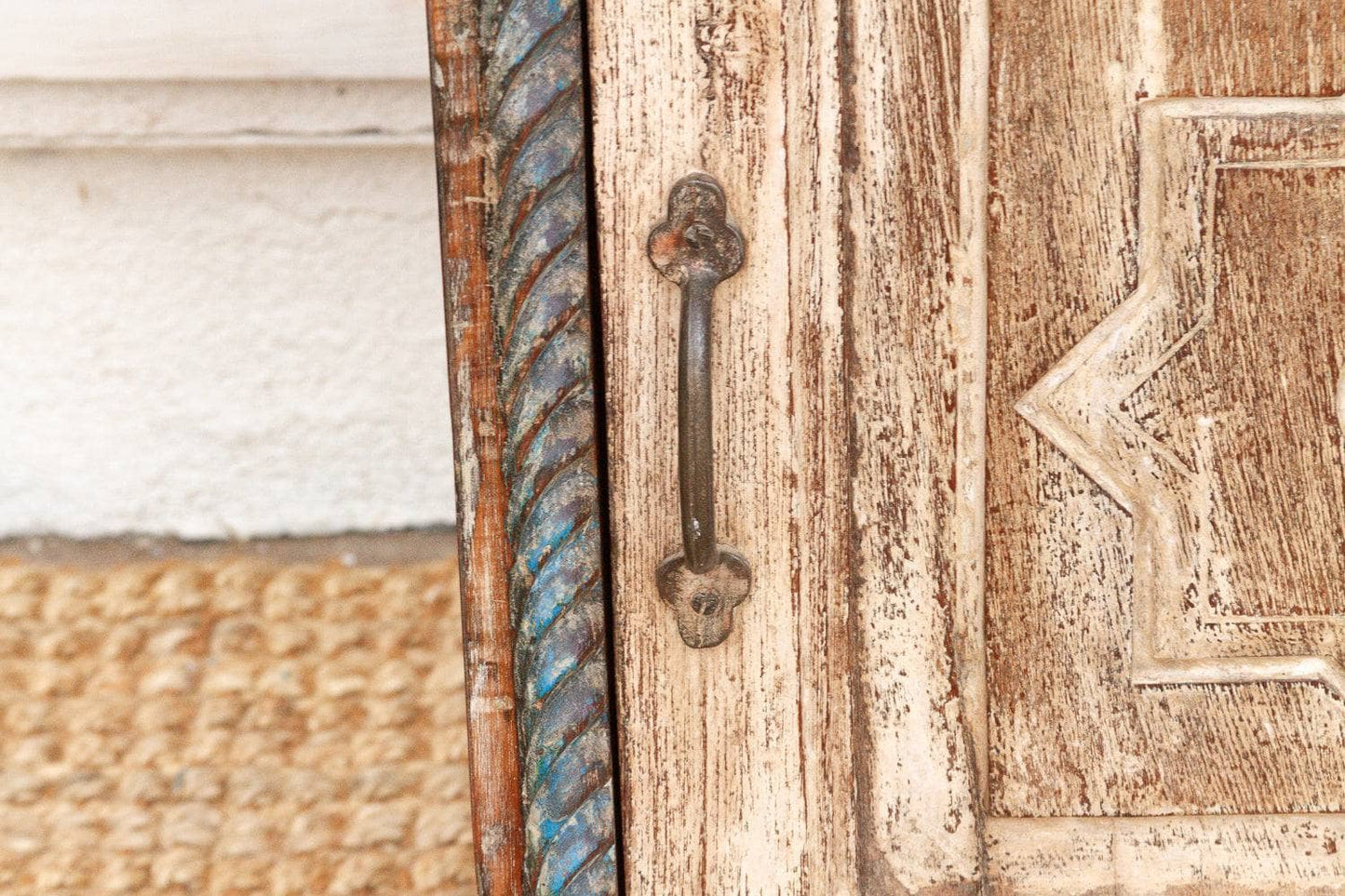 Close-up of a wooden door with a metal handle and decorative carvings.
