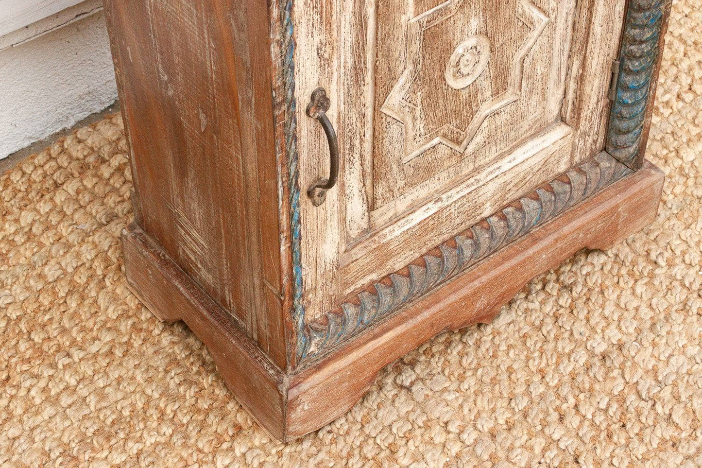 Wooden cabinet with decorative carvings on a textured surface