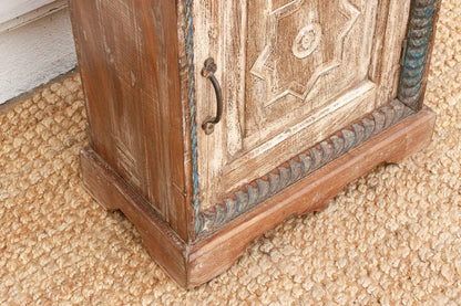 Wooden cabinet with decorative carvings on a textured surface