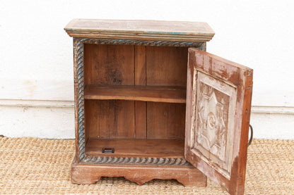Wooden cabinet with open door on a textured surface