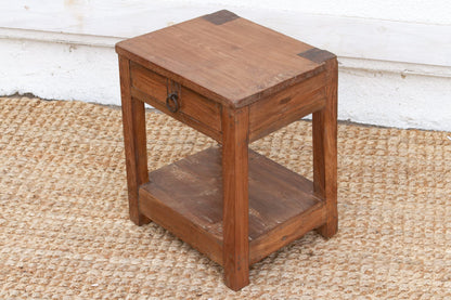 Wooden side table with a drawer on a textured floor