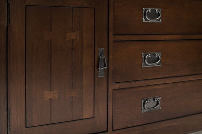 Close-up of a dark brown wooden cabinet door with a latch and three matching drawers with metal pull handles.