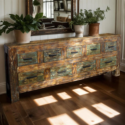 Wooden dresser with greenish patina in a room with plants and a mirror.