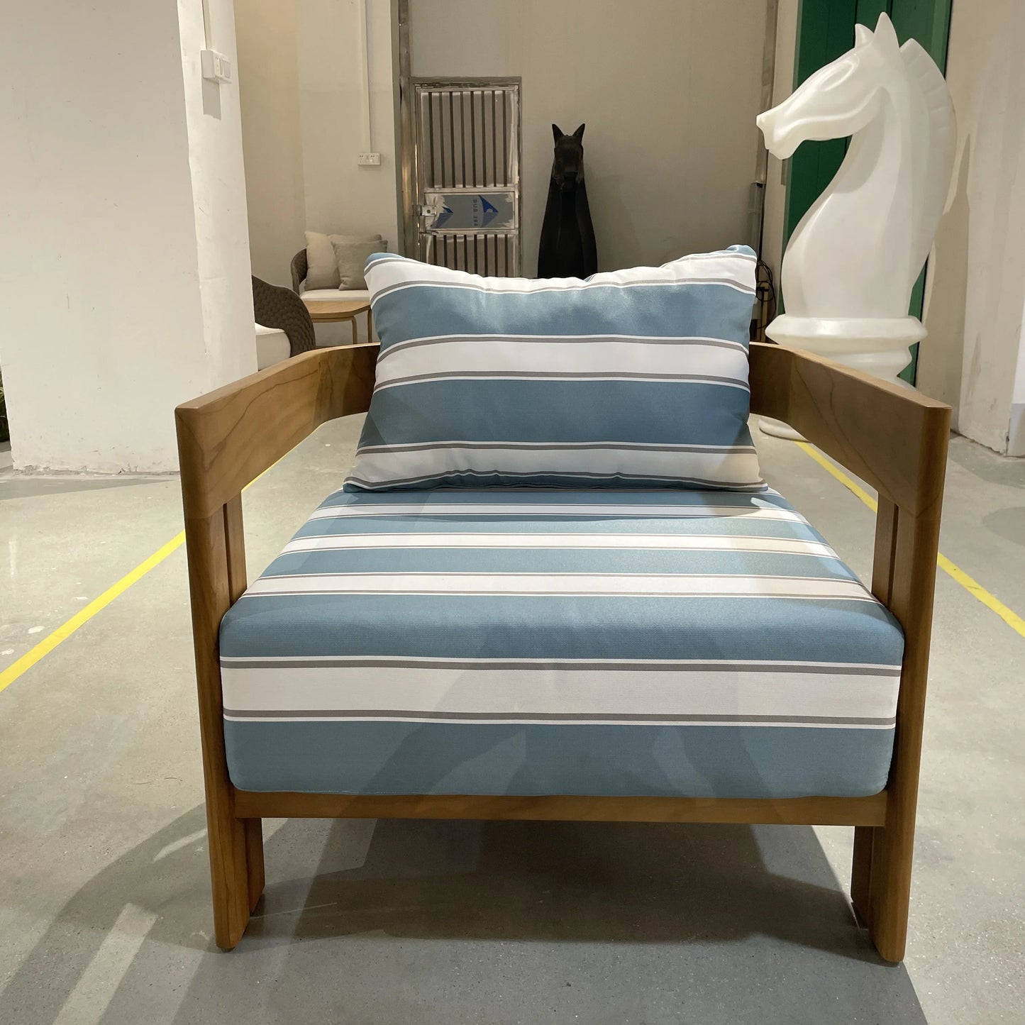 Chair with blue and white striped cushion and pillow in a room setting.