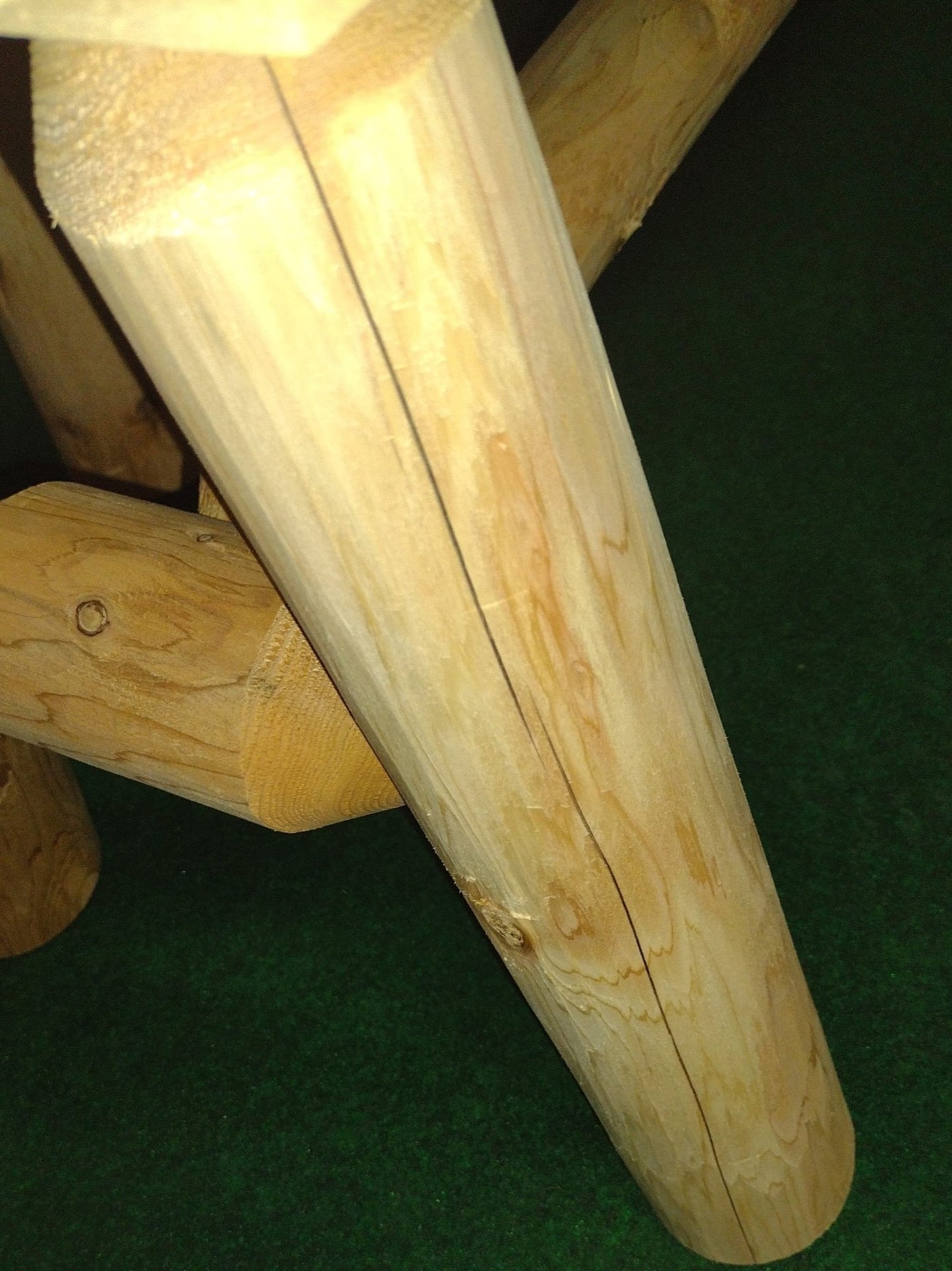 Close-up of a wooden stool with a green floor background